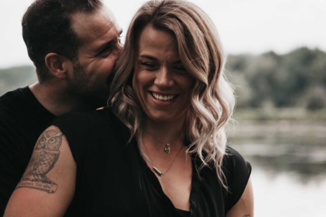 man hugging woman beside body of water