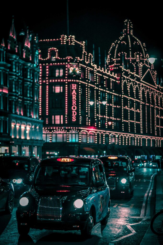 black taxi in the street passing trough Harrods Mall during nighttime