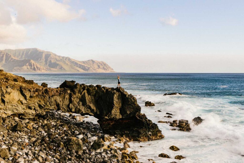 person on cliff near body of water