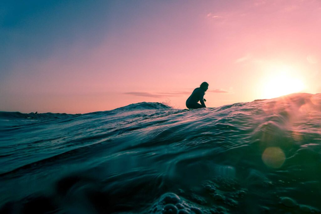 man surfing on ocean water during golden hour