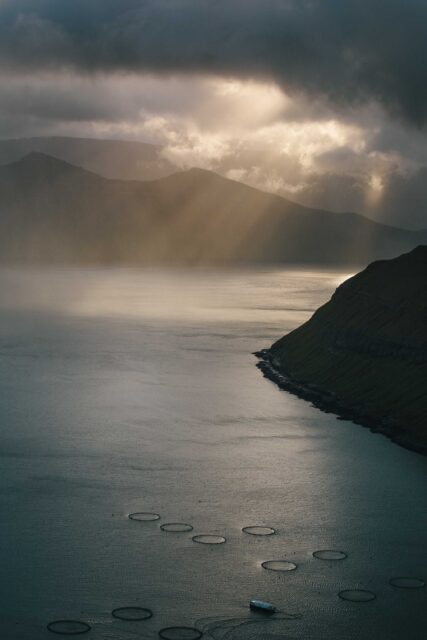 mountain near body of water under cloudy sky