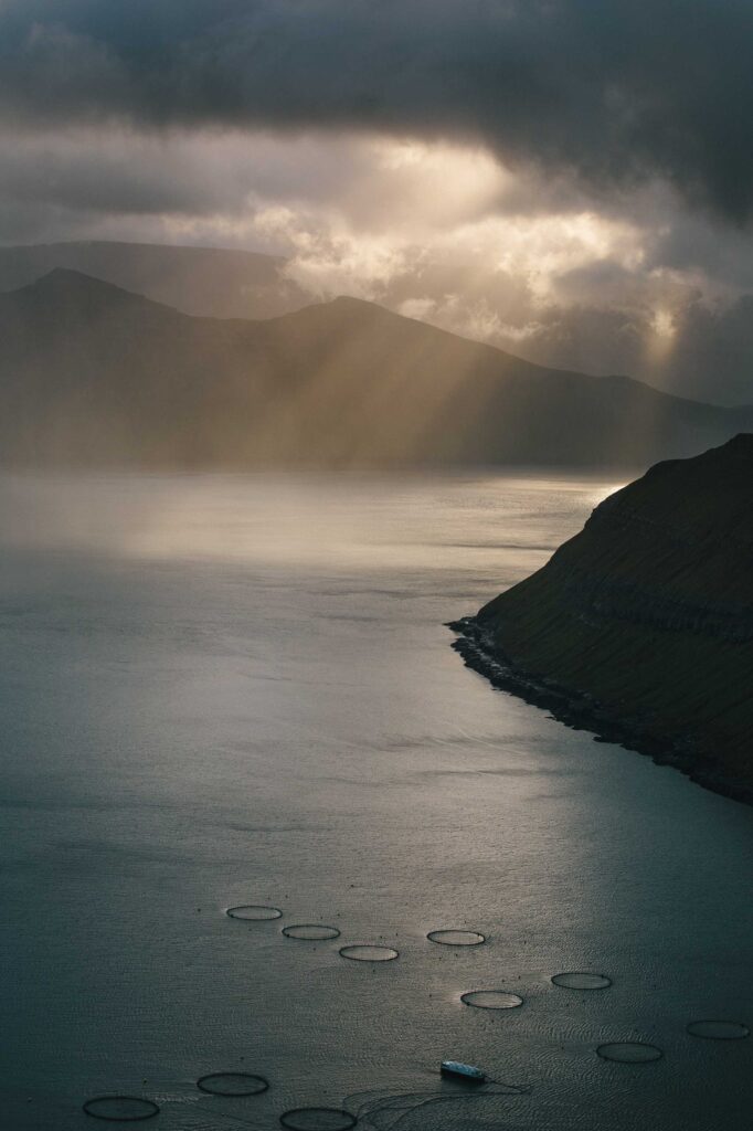 mountain near body of water under cloudy sky