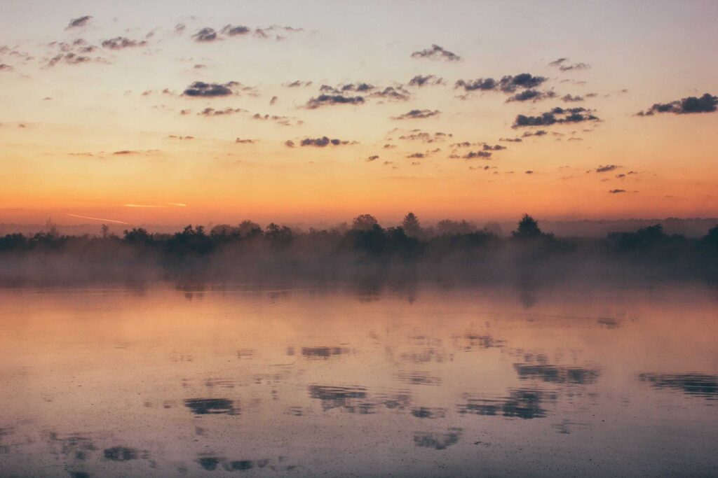 landscape photography of body of water across mountain at sunset