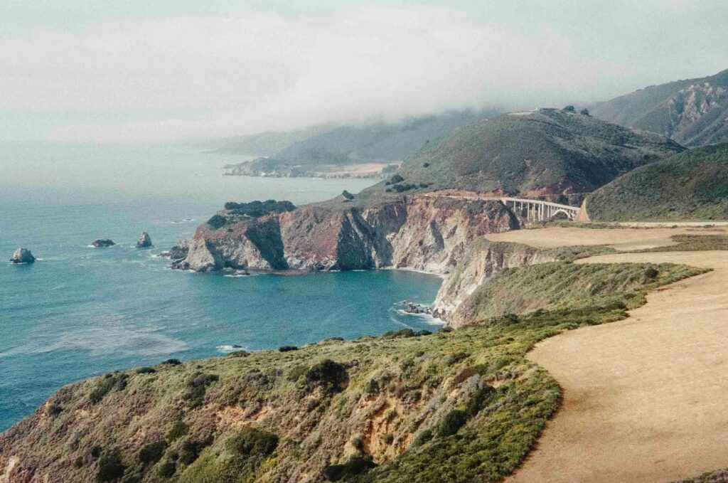 green and brown mountain beside body of water during daytime