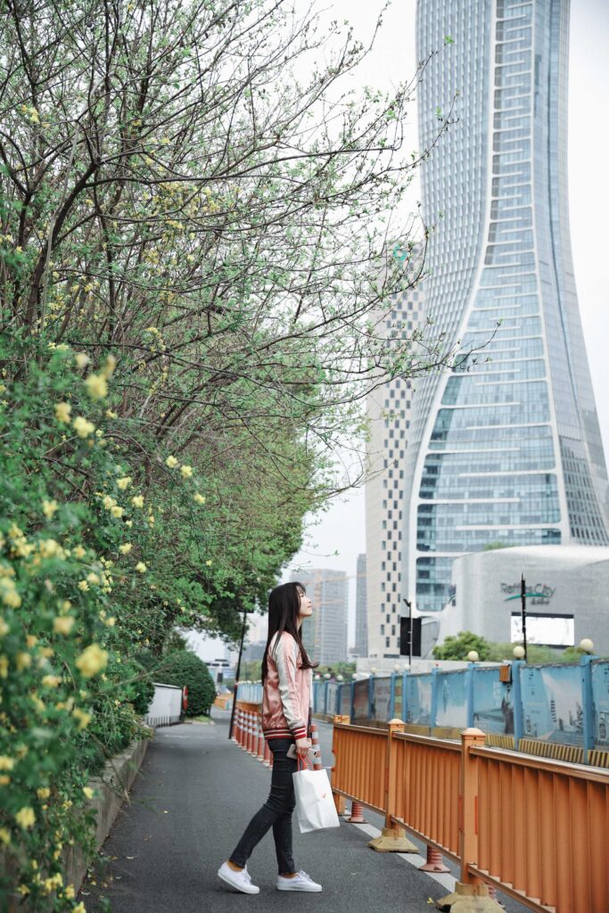 woman in black jacket standing near green tree during daytime