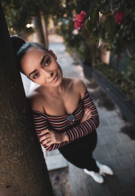 woman in black and white striped long sleeve shirt leaning on brown tree
